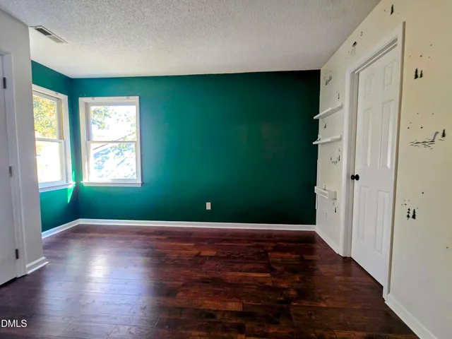 a view of an empty room with window and wooden floor