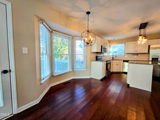 a open kitchen with stainless steel appliances granite countertop a stove top oven a refrigerator and a wooden floor