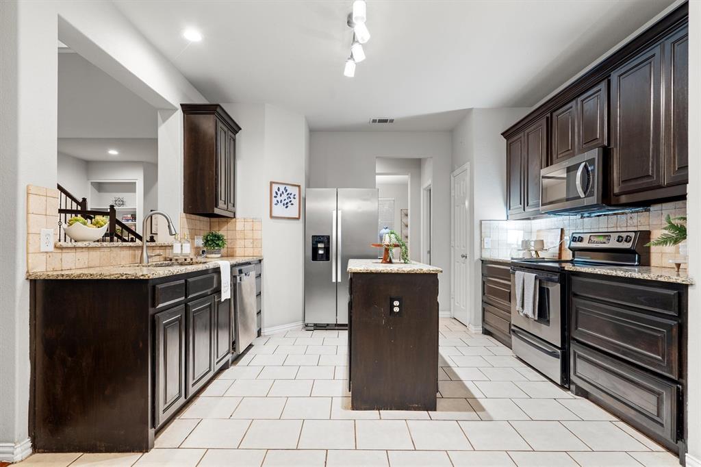 1501 Valley Creek Road Denton, TX 76205 - Photo 12 of 40 a kitchen with stainless steel appliances granite countertop a stove refrigerator and a microwave