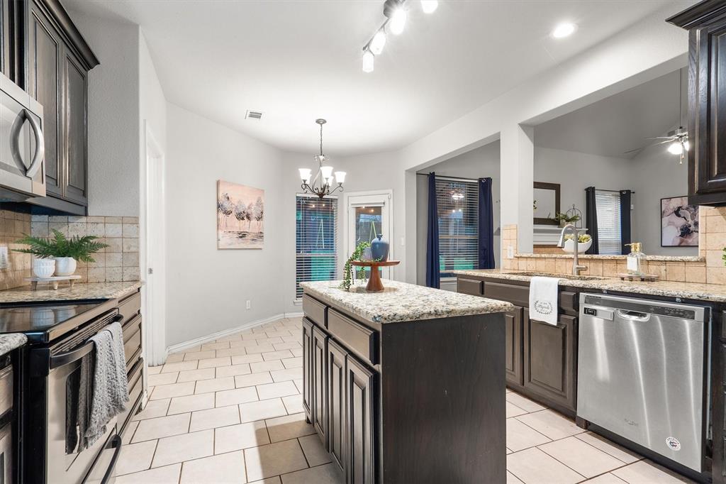 1501 Valley Creek Road Denton, TX 76205 - Photo 14 of 40 a kitchen with granite countertop cabinets a sink a stove and a refrigerator