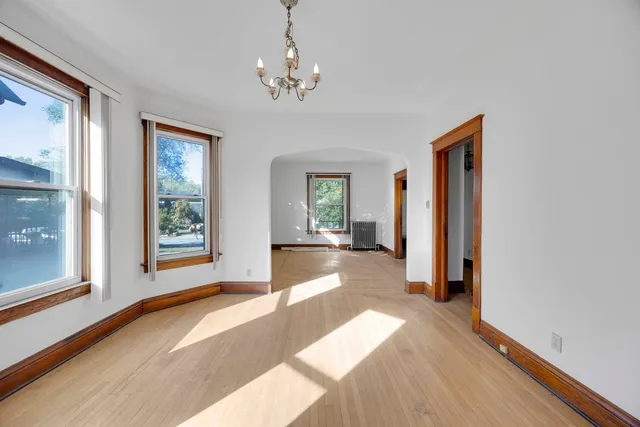 a view of a hallway with wooden floor and chandelier
