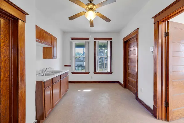 a view of an empty room with window and chandelier fan