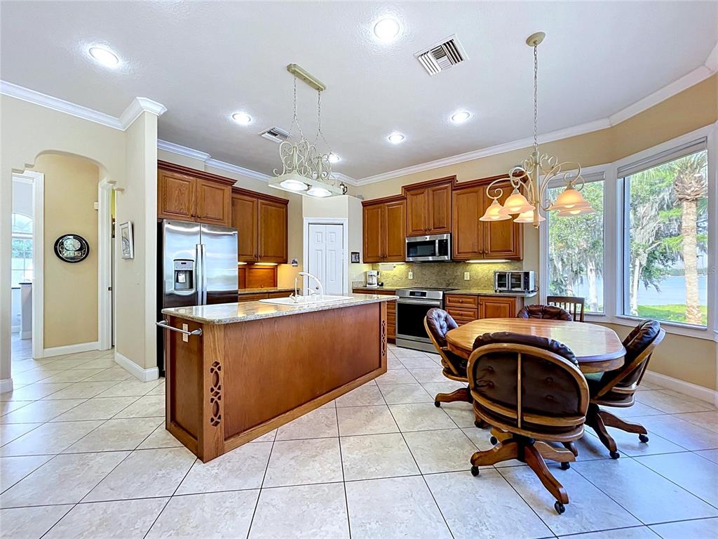 1360 South Waterview Drive Inverness, FL 34450 - Photo 46 of 100 a kitchen with stainless steel appliances granite countertop a stove top oven a sink dishwasher a refrigerator and a dining table with the living room view