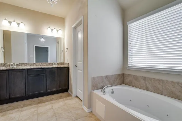 a bathroom with a tub a sink and a large mirror