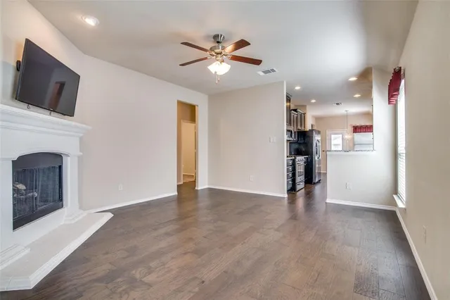 a view of an empty room with kitchen and a fireplace
