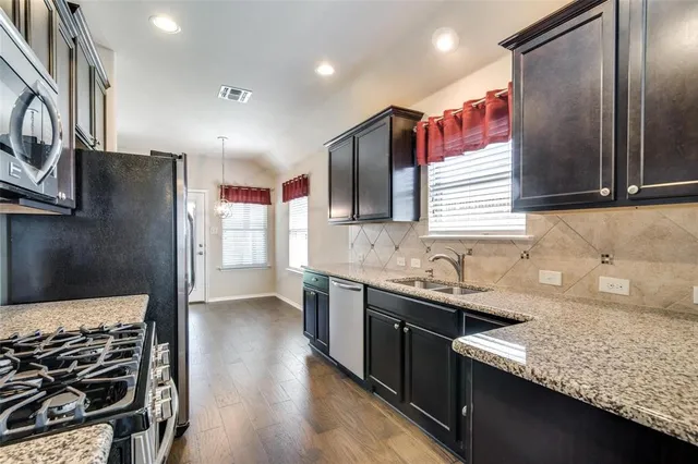 a kitchen with stainless steel appliances granite countertop a sink stove and refrigerator