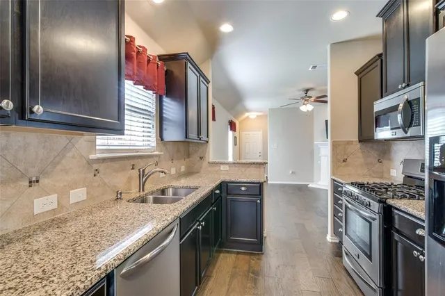 a kitchen with granite countertop a sink stove and cabinets