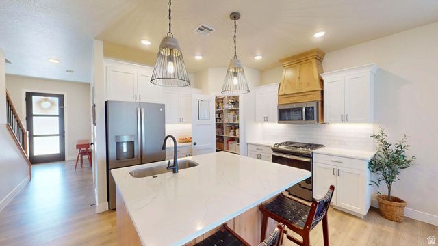 1127 4240 North Enoch, UT 84721 - Photo 7 of 56 Kitchen with stainless steel appliances, backsplash, light stone counters, a kitchen island with sink, and a kitchen bar