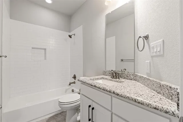a bathroom with a granite countertop sink a toilet and a bathtub