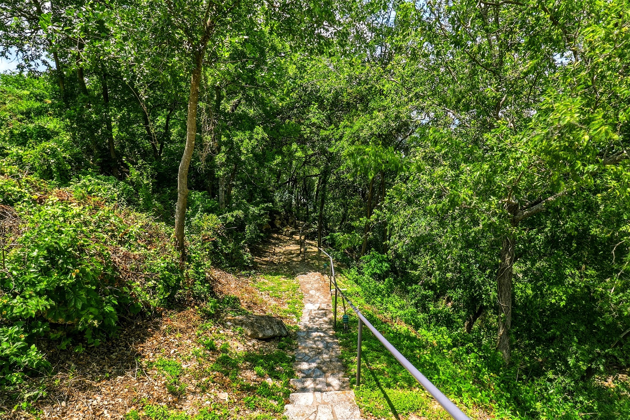 2918 Ranch Road 620, Unit 265 Austin, TX 78734 - Photo 31 of 40 A winding stone pathway with sturdy handrails descends through a lush, verdant landscape, inviting tranquil walks.