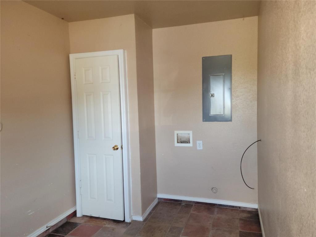 2782 Batey Road, Unit 2780 Collinsville, TX 76233 - Photo 7 of 9 Utility space featuring multi-toned tile flooring, light beige wall finishes, a white paneled door, and a wall-mounted electrical panel/ mud room