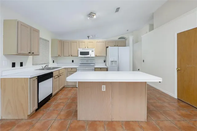 a kitchen with a sink a stove a refrigerator a white building and white cabinets