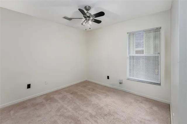 an empty room with a window and a ceiling fan