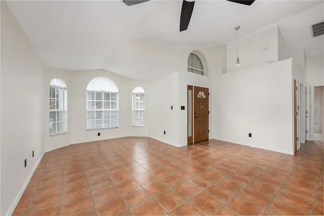 a view of an empty room with chandelier fan and window