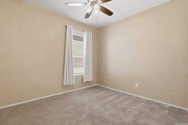an empty room with a chandelier fan and windows