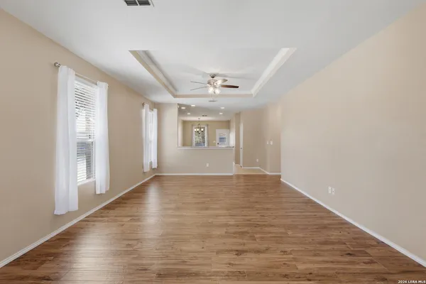 a view of an empty room with a window and wooden floor