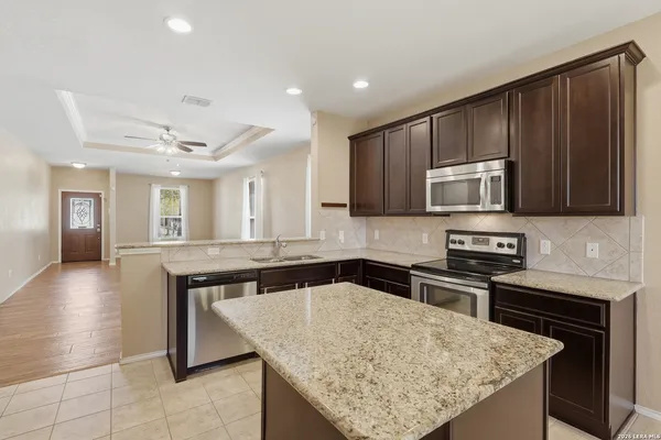 a kitchen with stainless steel appliances granite countertop a sink dishwasher stove and microwave with wooden floor
