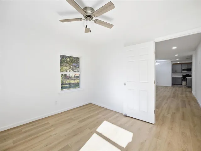 an empty room with wooden floor and a ceiling fan