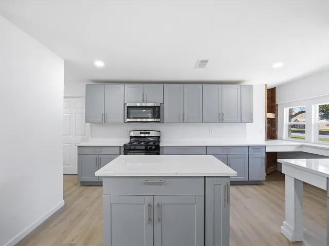 a kitchen with a sink a stove cabinets and wooden floor
