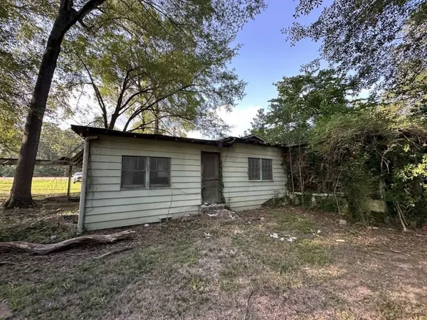 a view of a barn with a small yard and a large tree