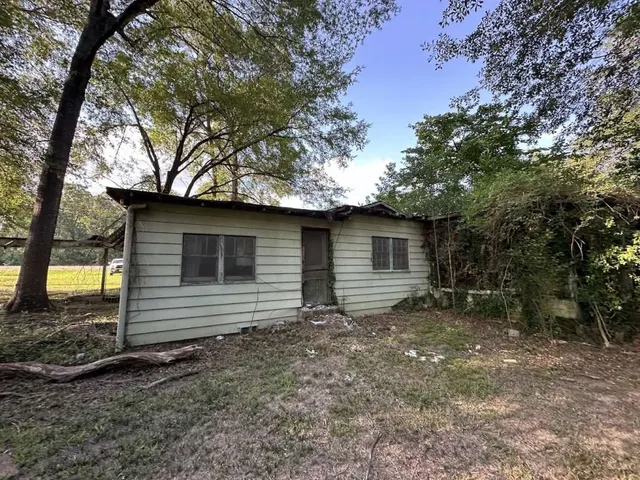 a view of a barn with a small yard and a large tree