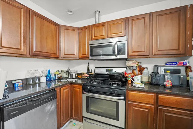 a kitchen with stainless steel appliances granite countertop a stove a sink dishwasher and cabinets with wooden floor