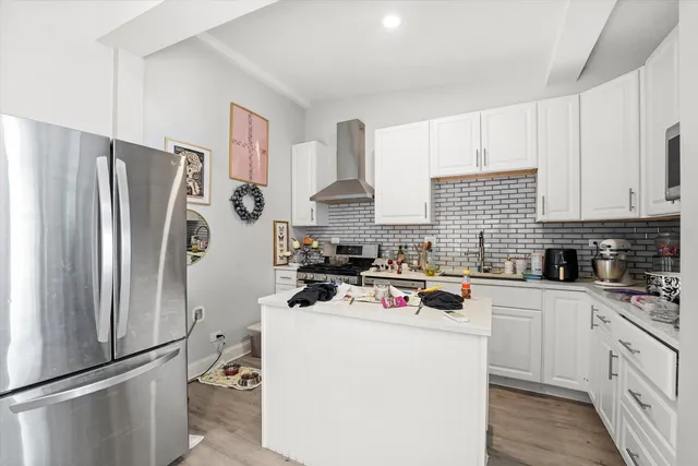 a kitchen with a refrigerator a sink dishwasher a stove and white cabinets with wooden floor