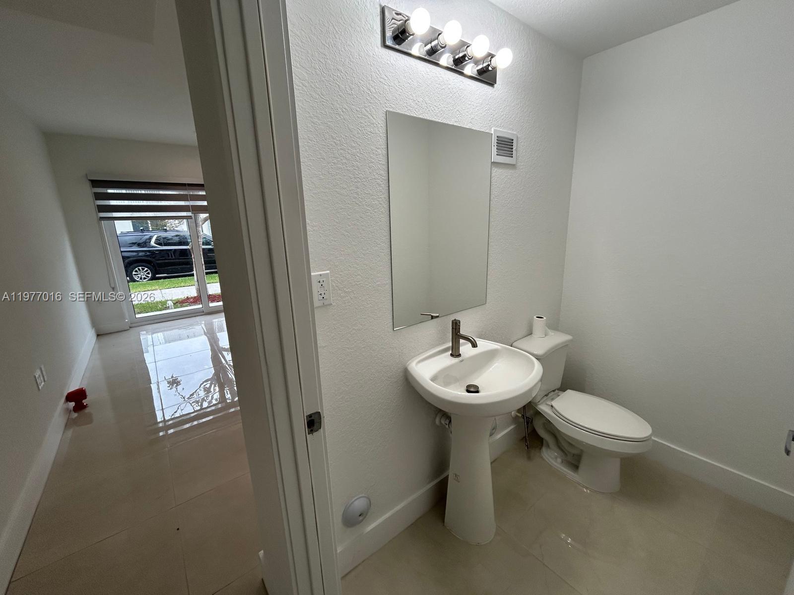 25814 Southwest 144th Court, Unit 2 Homestead, FL 33032 - Photo 6 of 25 a bathroom with a toilet a sink and mirror