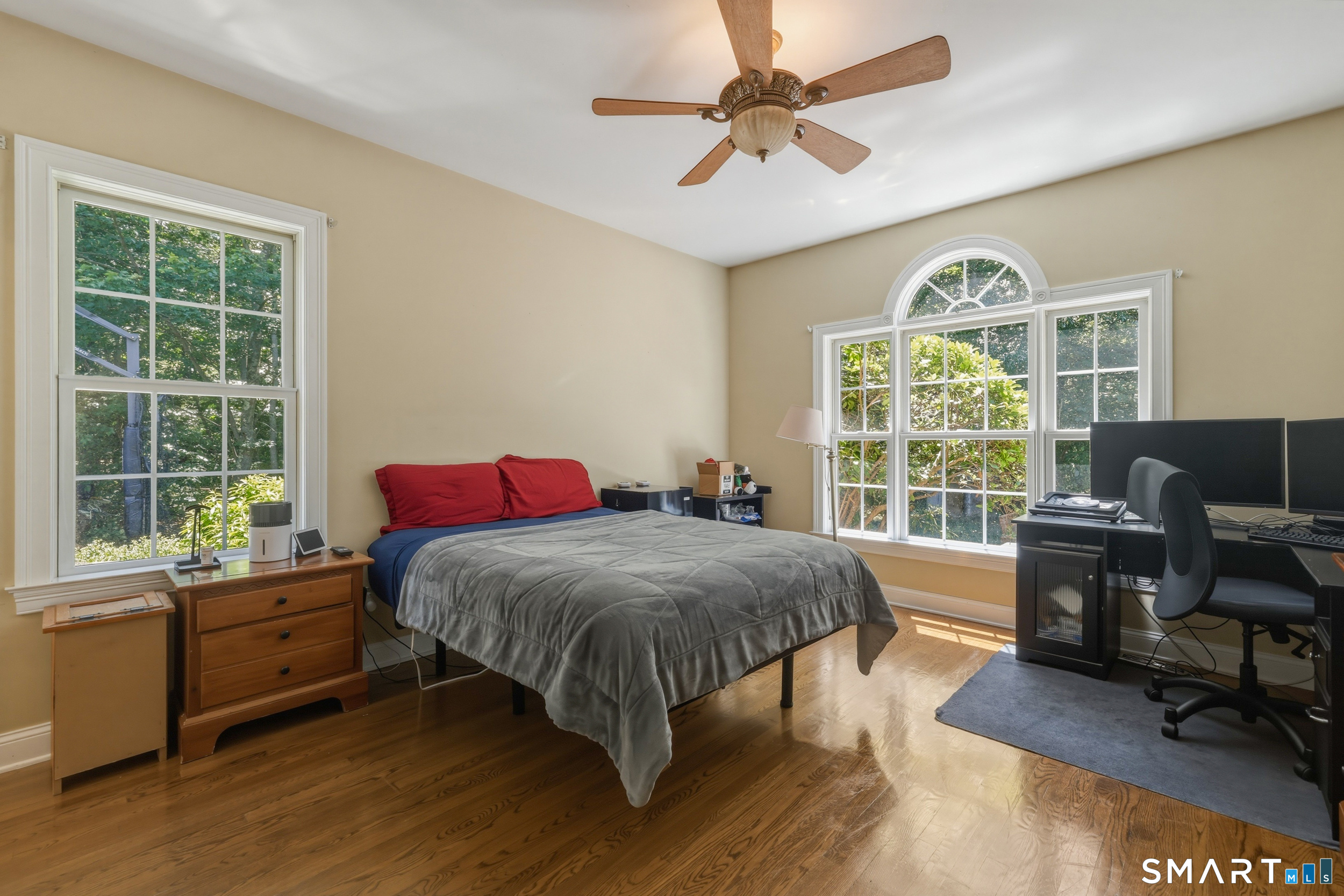 122 Lower Road Guilford, CT 06437 - Photo 18 of 40 A second main-level ensuite bedroom features hardwood flooring, a Palladian window, and a ceiling fan, along with a full private bath; ideal for guests or extended stays.