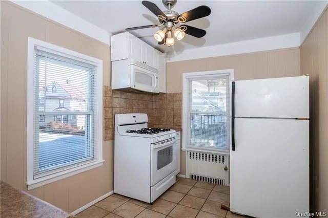 a kitchen with stainless steel appliances granite countertop a refrigerator a stove a sink a with a window and a chandelier