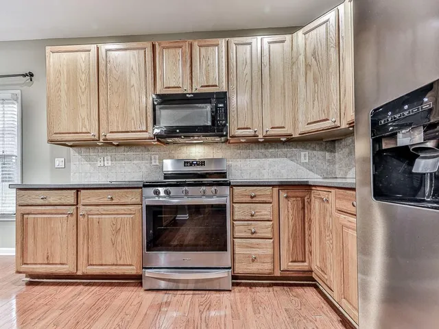 a kitchen with stainless steel appliances granite countertop a stove a microwave and a white cabinets