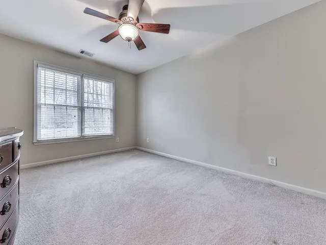 an empty room with windows and ceiling fan