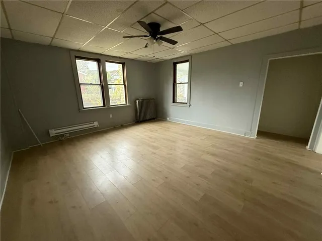 an empty room with windows and ceiling fan