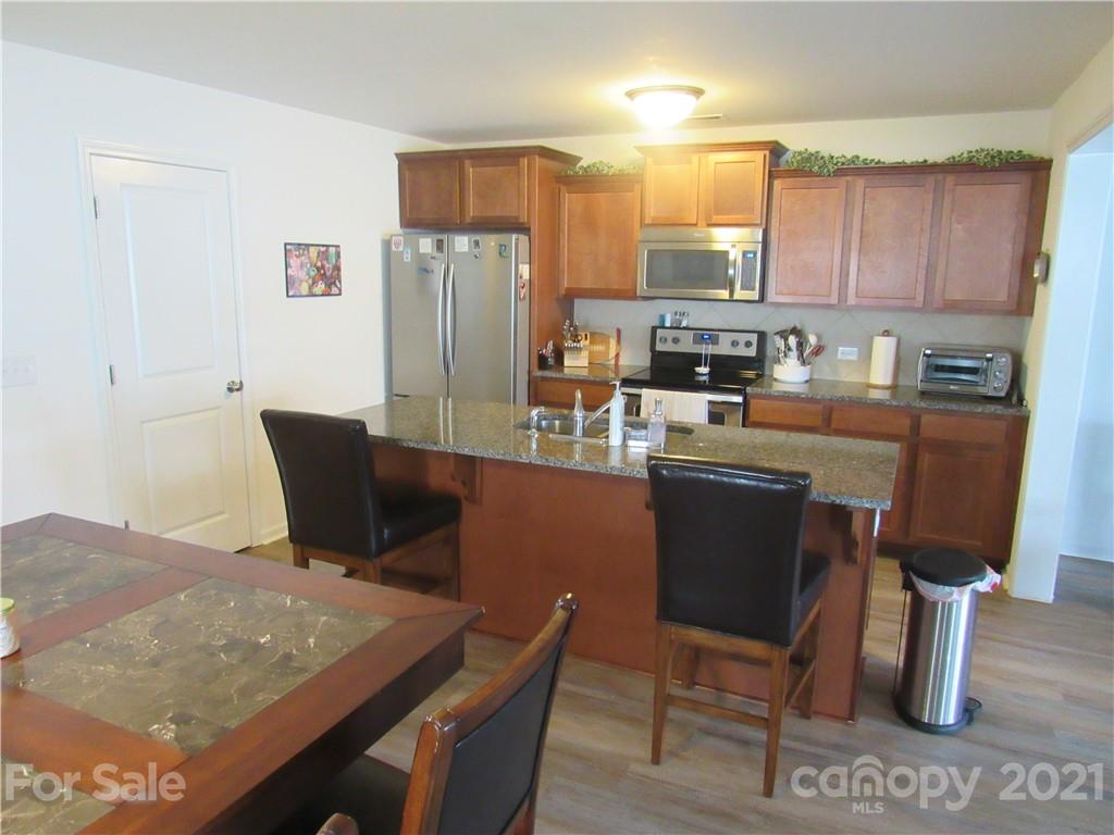 8188 Thornton Street Locust, NC 28097 - Photo 18 of 36 a kitchen with stainless steel appliances granite countertop a table chairs stove refrigerator and cabinets