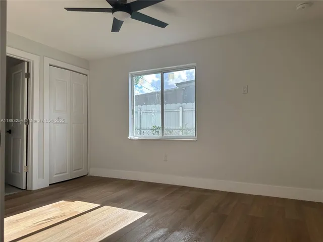 an empty room with wooden floor fan and windows
