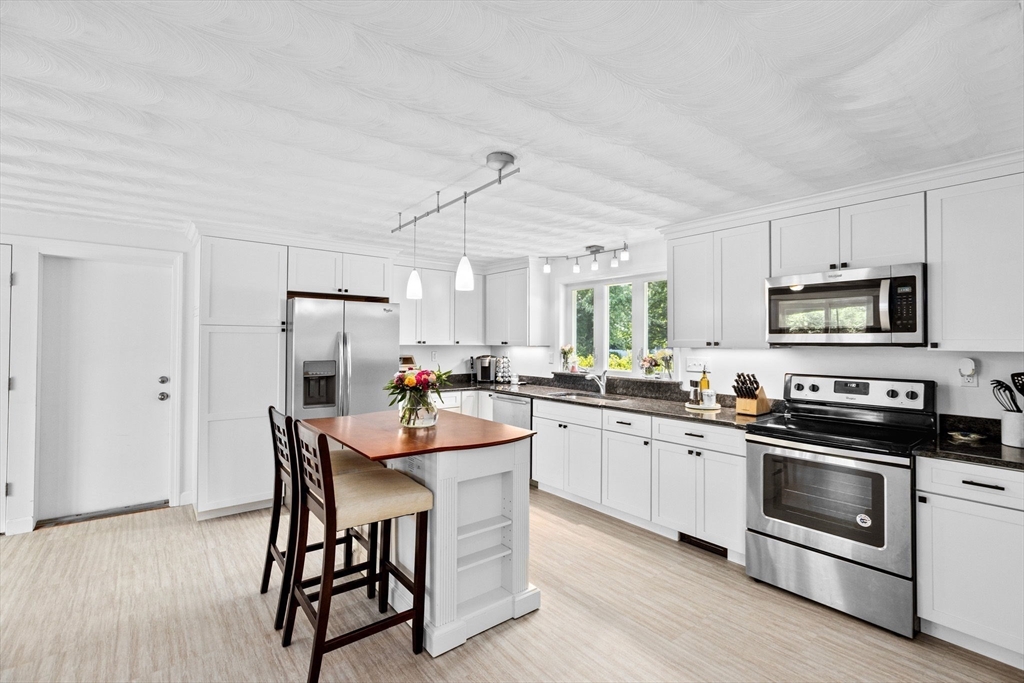 13 Pinewood Drive Framingham, MA 01701 - Photo 8 of 21 a kitchen with stainless steel appliances a stove a sink dishwasher a refrigerator with white cabinets and wooden floor
