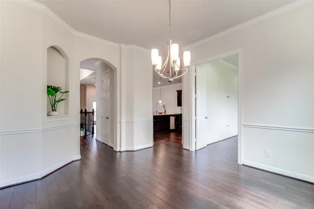 a view of a hallway with wooden floor and a chandelier