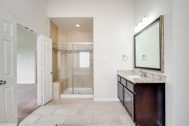 a bathroom with a granite countertop sink a mirror and a shower