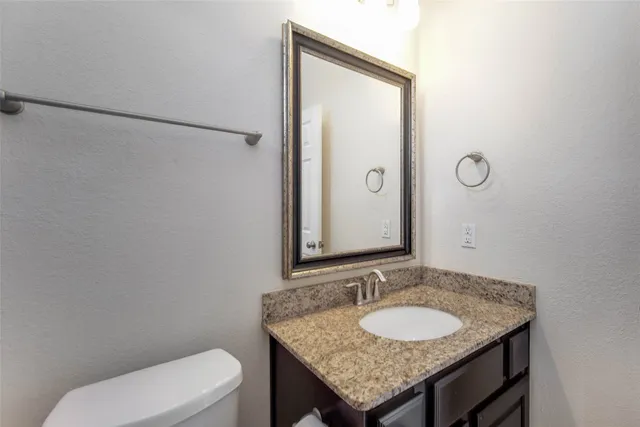 a bathroom with a granite countertop toilet sink and mirror