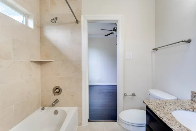 a bathroom with a granite countertop bathtub shower sink vanity and toilet