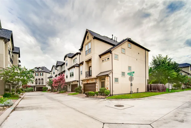 a view of a white building among the street and trees
