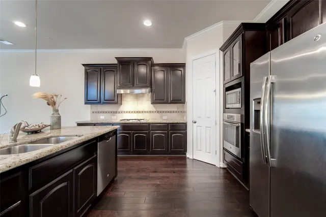 a kitchen with stainless steel appliances granite countertop a refrigerator a sink and a stove