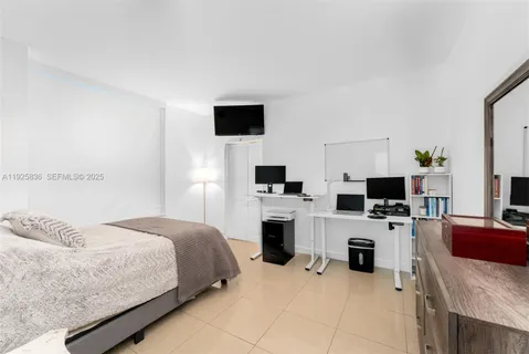 a spacious bedroom with a bed and a flat screen tv