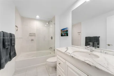 a bathroom with a granite countertop bathtub shower sink vanity and toilet