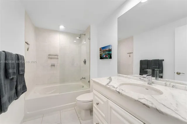 a bathroom with a granite countertop bathtub shower sink vanity and toilet