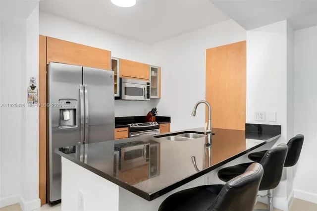 a kitchen with stainless steel appliances granite countertop a sink a stove and refrigerator
