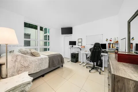 a bedroom with a bed flat screen tv and chairs
