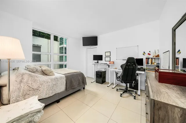 a bedroom with a bed flat screen tv and chairs
