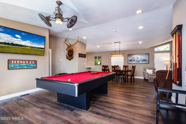 a living room with furniture pool table flat screen tv and windows
