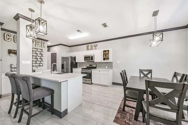 a kitchen with a dining table chairs and white cabinets